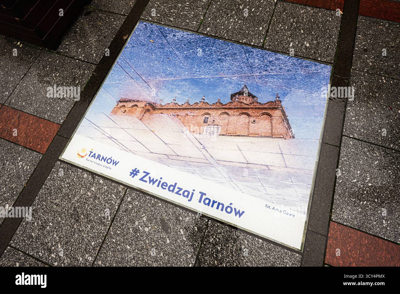 Tarnow, Polen - 10. Oktober 2025: Eine Fußgängerplatte, die Tarnów mit einem historischen Gebäudebild und einem Reise-Hashtag fördert. Stockfoto