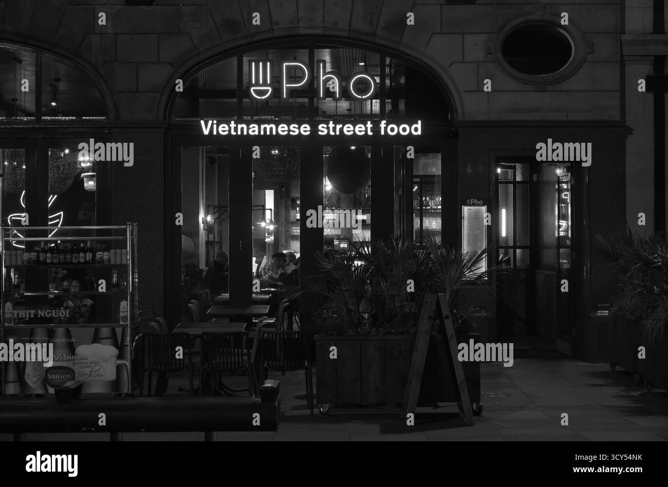 Schwarz-weiße Nacht Blick auf Pho vietnamesisches Street Food Restaurant in der Castle Street, Liverpool, mit leuchtenden Schildern und Restaurants im Inneren. Stockfoto
