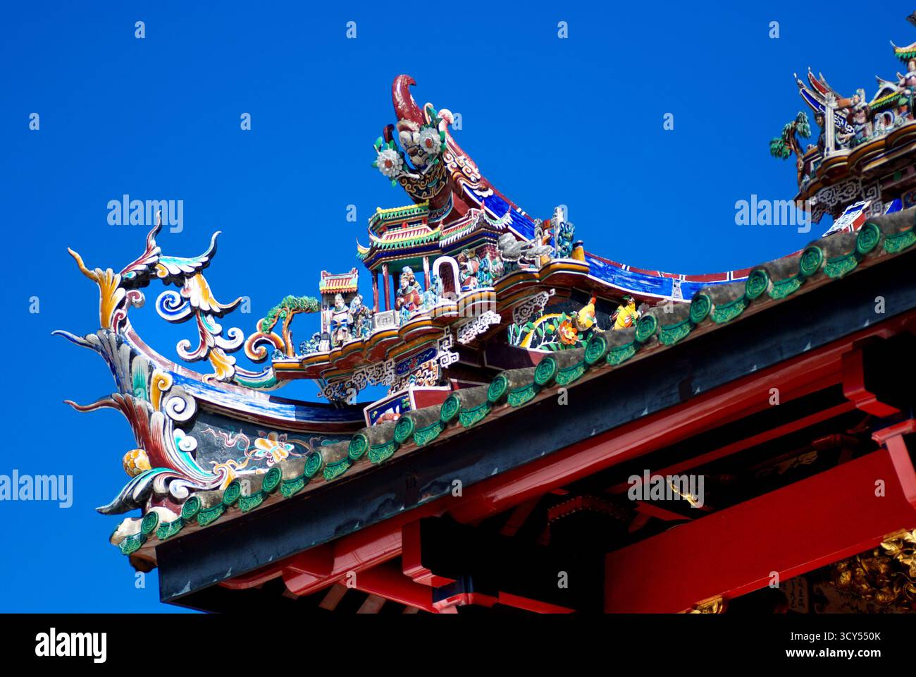 Kompliziertes chinesisches Tempeldach mit bunten Figuren und mythischen Kreaturen vor dem blauen Himmel Stockfoto