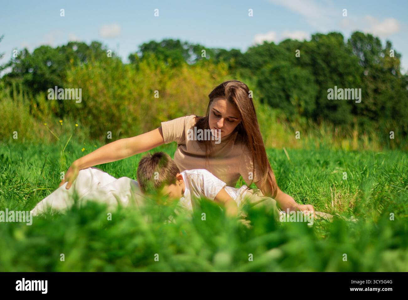 Mutter mit Kind, die Spaß im öffentlichen grünen Park hat. Glückliche Mutter lacht zusammen mit dem Sohn. Hochwertige Freizeit im Freien. Stockfoto