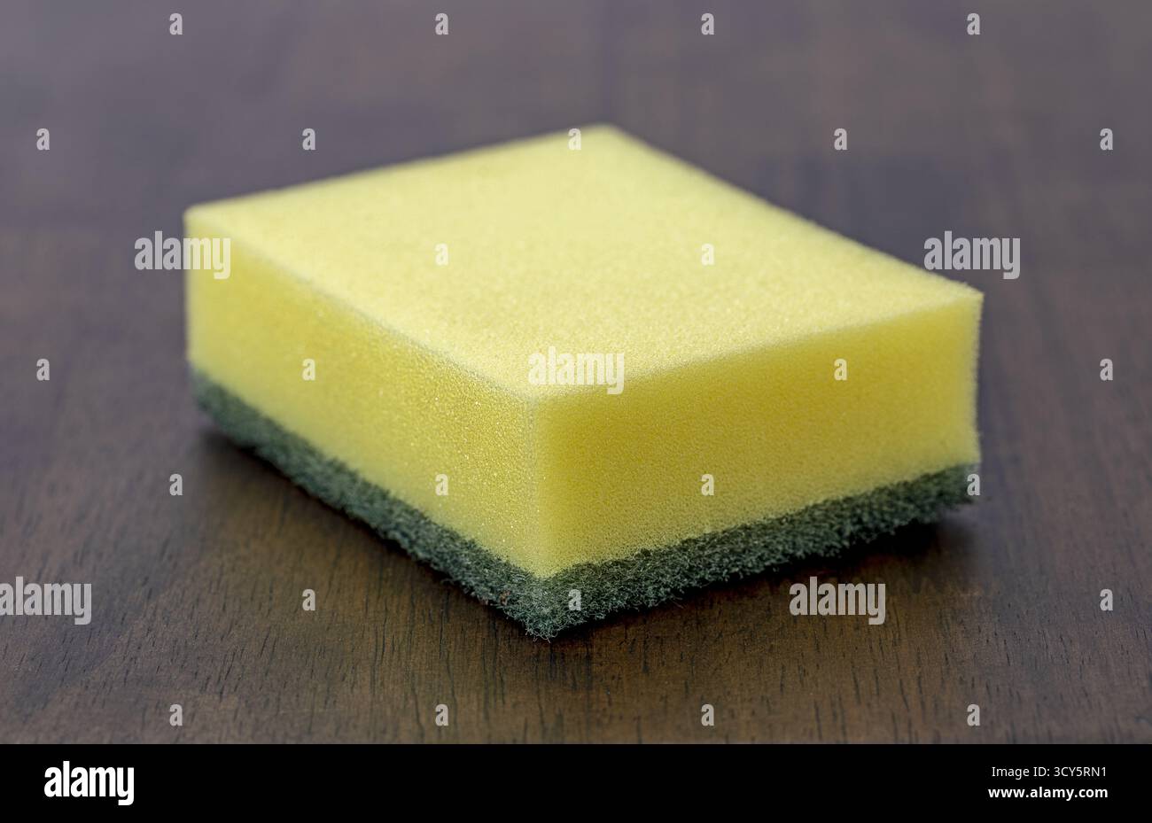 Ein gelber Schwamm grüner Scheuerschwamm Küchenschwamm Geschirrschwamm Haushaltsreinigung Poröse Textur rechteckige Form Hygienewerkzeug Holztisch Stockfoto