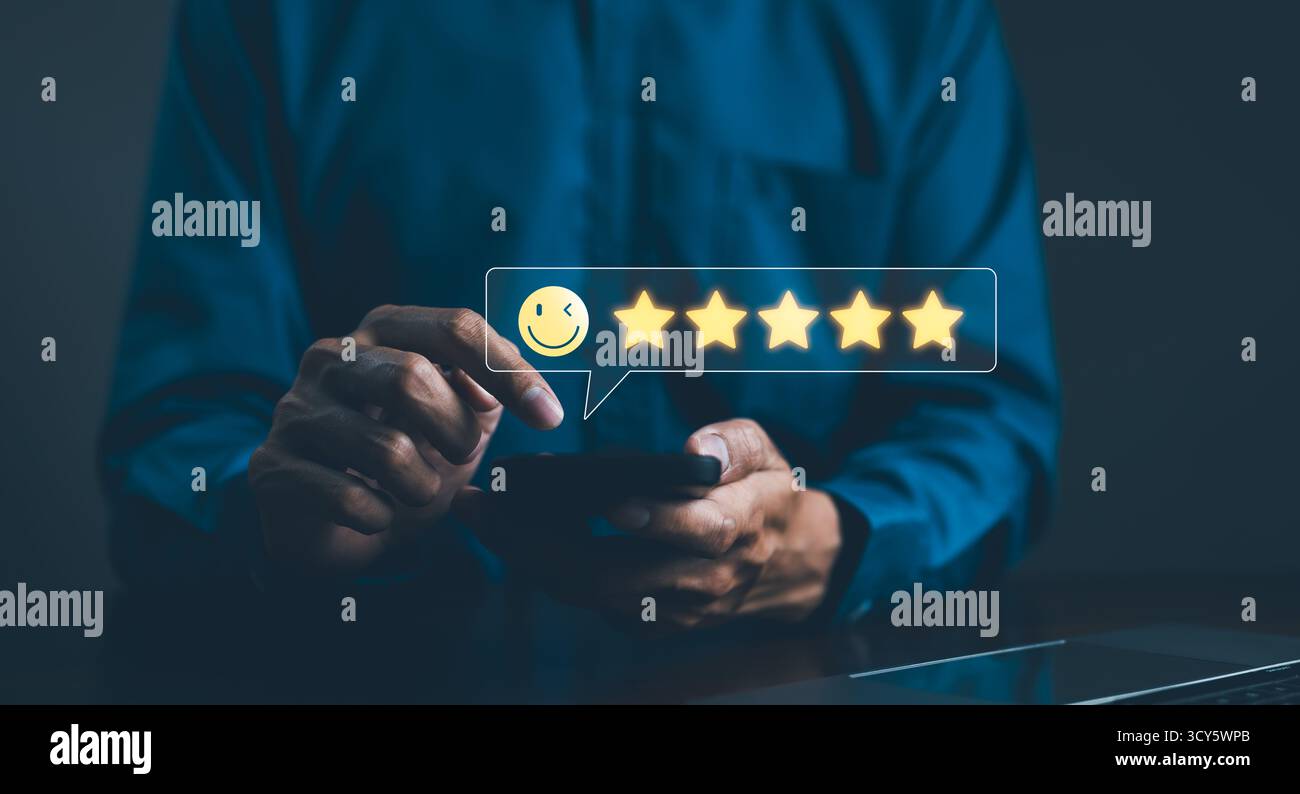 Konzept Der Umfrage Zur Kundenbewertung Zur Zufriedenheit Mit Feedback. Eine Person verwendet ein Smartphone, um eine 5-Sterne-Bewertung mit einem Smiley-Symbol zu vergeben Stockfoto