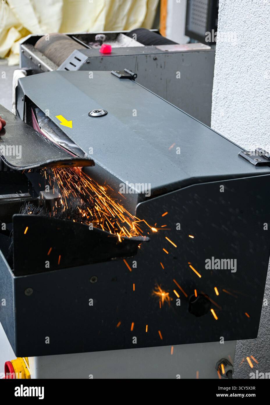 Skikantenschleifmaschine zum Schärfen eines Skis mit Funken, die in einer Werkstatt fliegen. Stockfoto