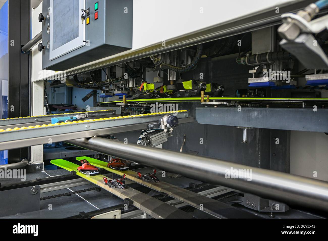 Skischuhe, die an Skier gebunden sind, auf einer automatisierten industriellen Produktionslinie in einer Fabrik. Stockfoto