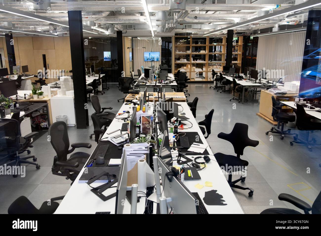 Computer auf Schreibtischen und Stühlen an Arbeitsplätzen in der modernen City of London Büroeinrichtung London England Großbritannien 2025 Großbritannien KATHY DEWITT Stockfoto