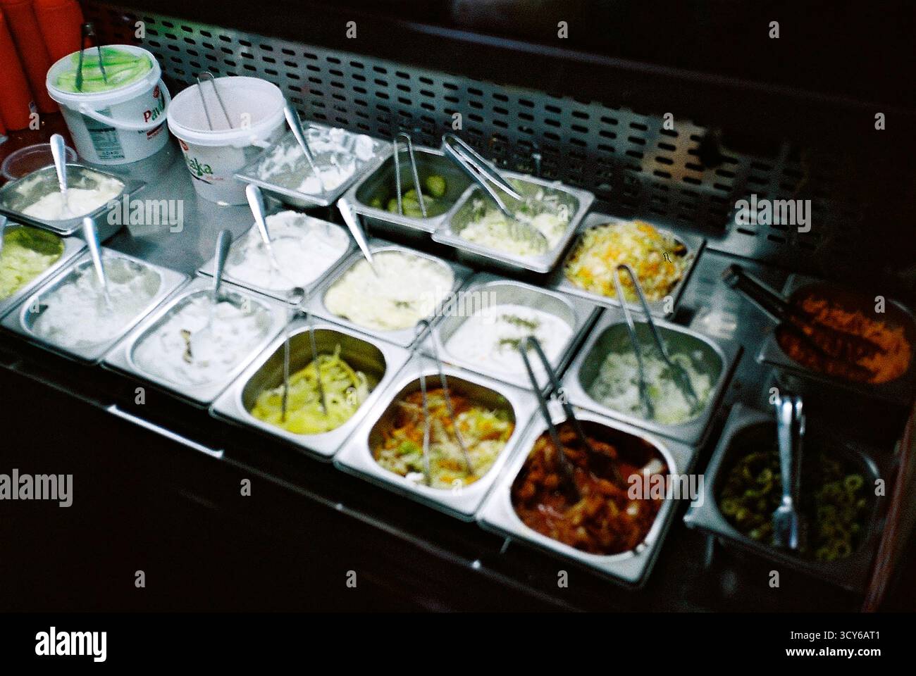 Blick in einen Kühlschrank mit Fast-Food-Saucen in der Nacht, aufgenommen auf Film mit sanftem analogem Glanz. Stockfoto