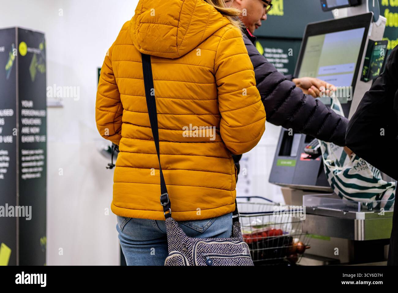 Epsom, London, Großbritannien, 17. Oktober 2025, Kunden, die Lebensmittel bei Automated Payment Tills bezahlen Stockfoto