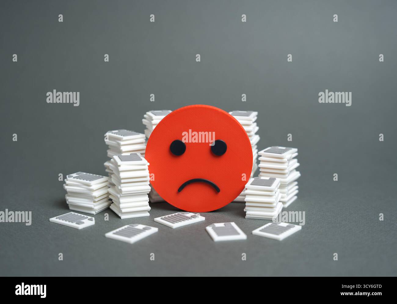 Ein trauriges, lächelndes Gesicht und Stapel von Dokumenten und Papieren. Hohe Bürokratie. Arbeitsrückstand. Bürostress, Büroüberlastung und Ineffizienz. Unternehmen Stockfoto