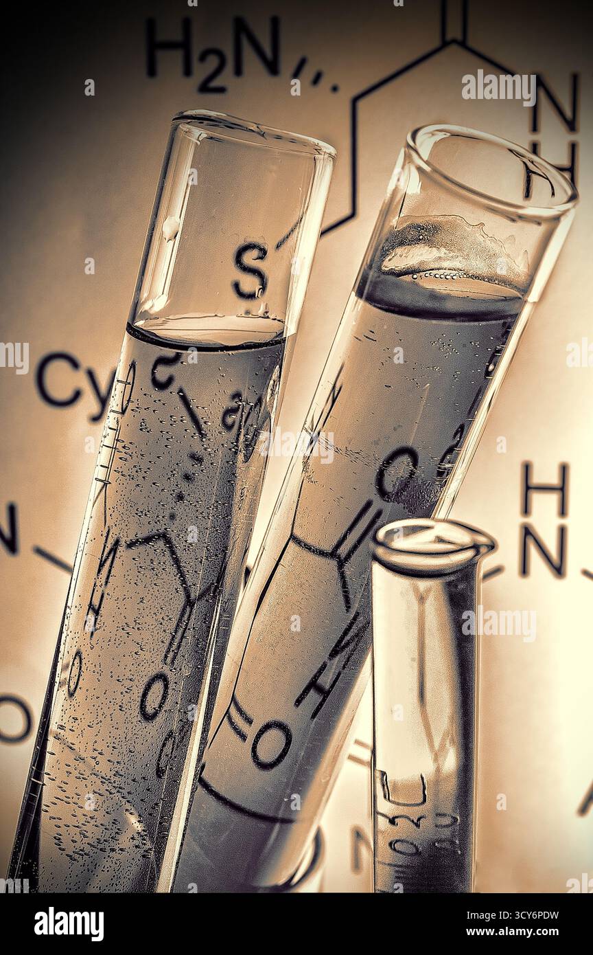Drei transparente Reagenzgläser, gefüllt mit klarer Flüssigkeit und Blasen, vor einem chemischen Diagramm platziert. Stockfoto