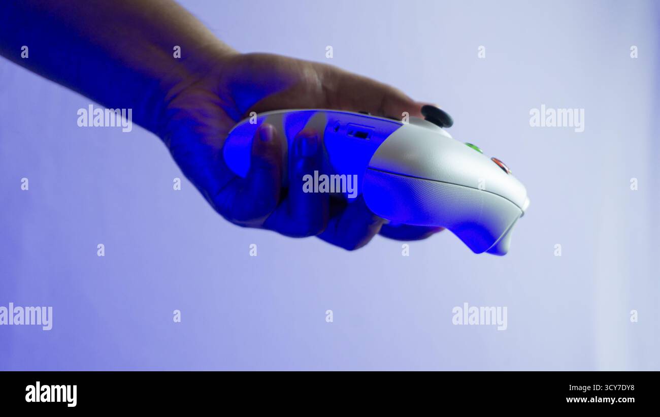 South Kalimantan, Indonesien - 07 14 2025 : weißer S|X-Controller der Xbox-Serie in einer Hand gehalten auf weißem Hintergrund unter blauem Umgebungslicht, zeigt min Stockfoto