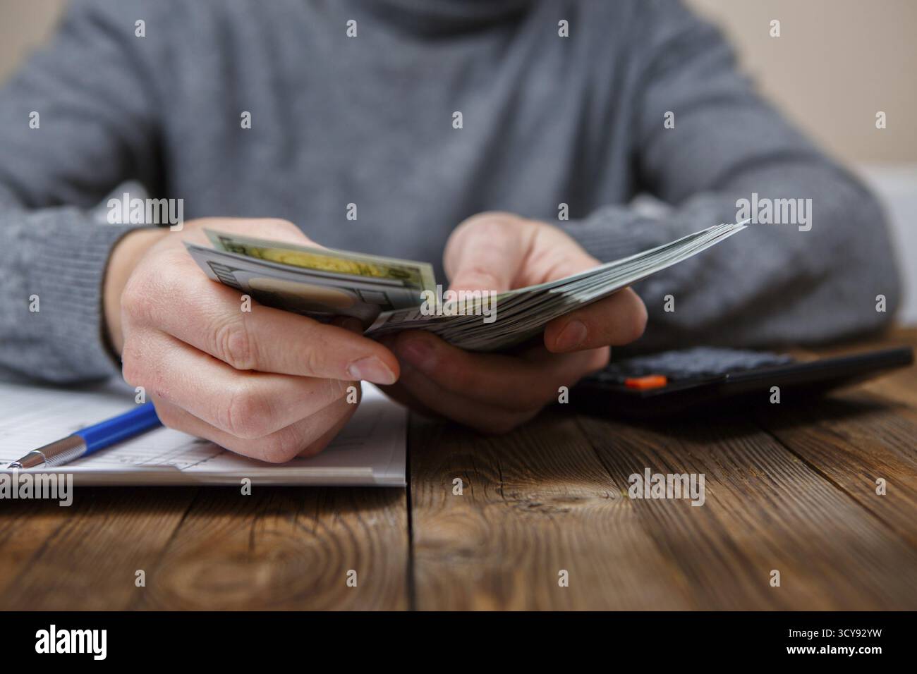 Kaukasische Hände zählen-Dollar-Banknoten auf dunklen Holztisch Stockfoto