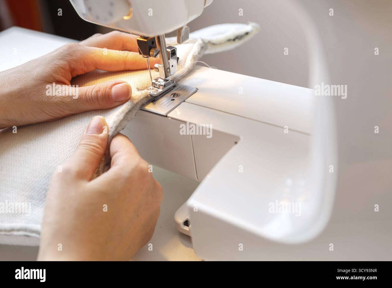 Foto von Mädchen, das zu Hause Stoff auf Nähmaschine bearbeitet Stockfoto