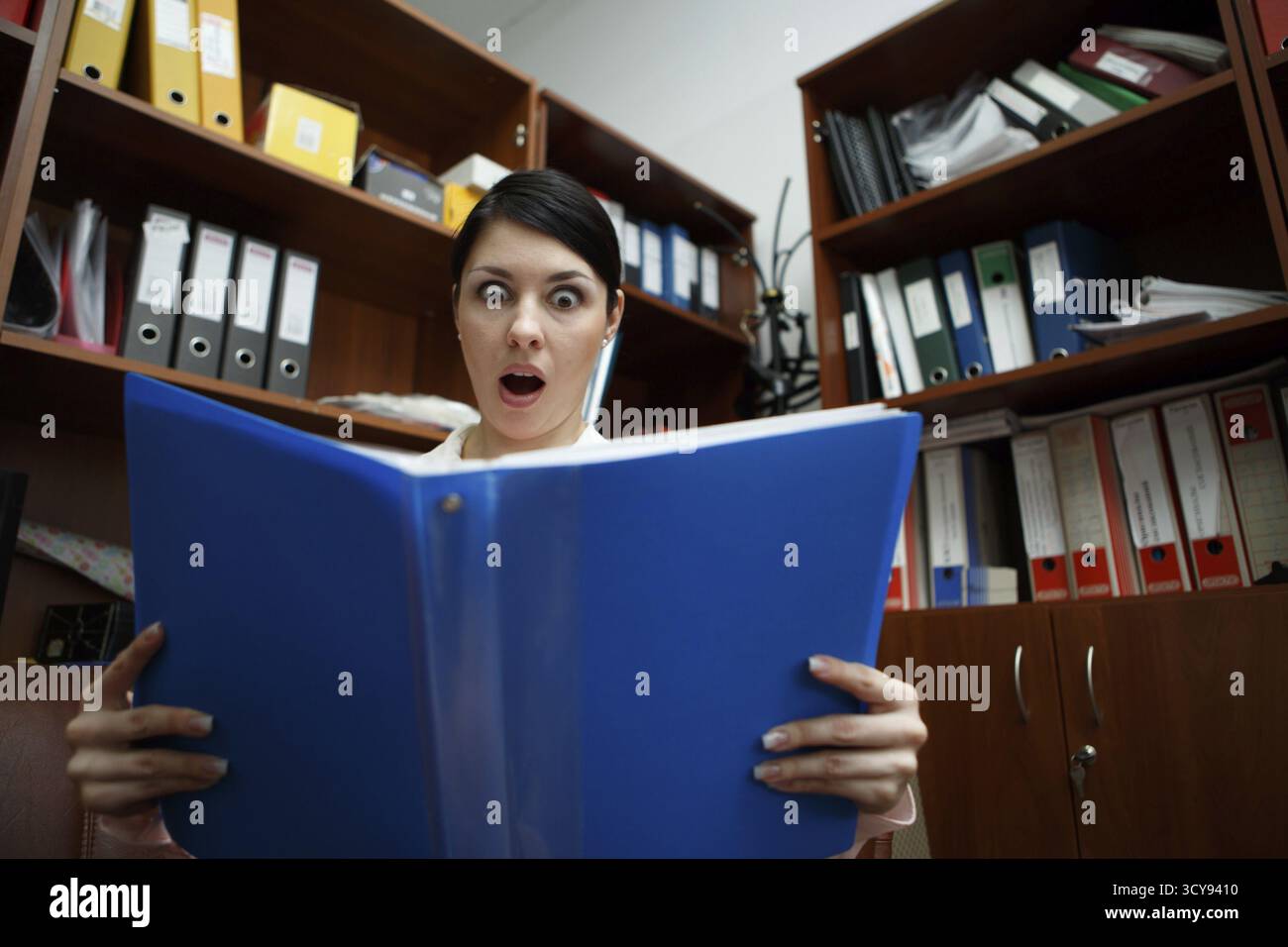 Überrascht, hübsche Frau, die auf offenen Ordner schaut Stockfoto