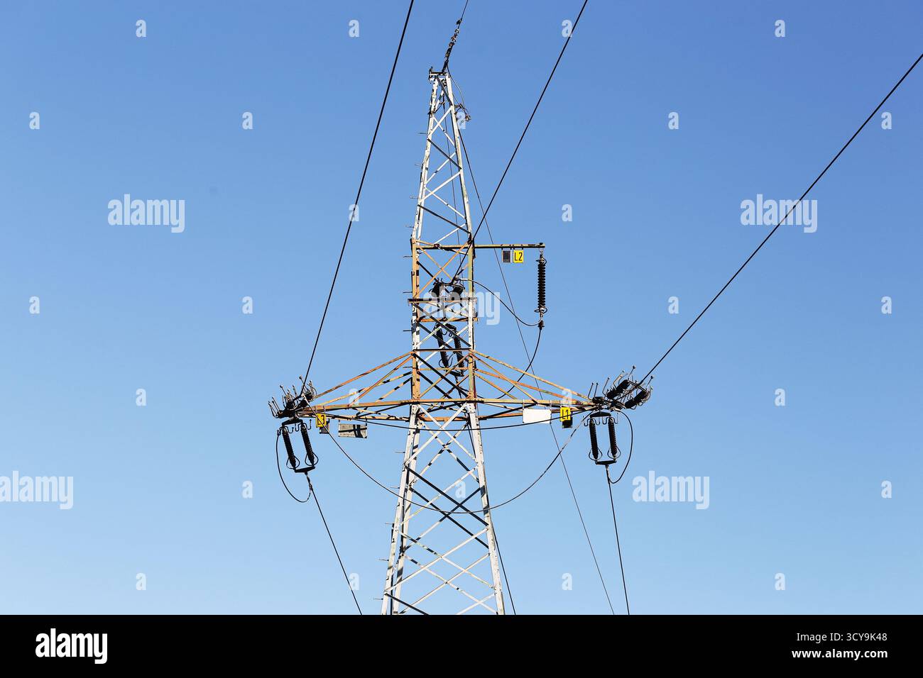 Hochspannungsnetzturm. Elektrische Übertragungsstruktur vor klarem blauem Himmel. Konzept des Energieverteilungsnetzes. Industriestrom. Stockfoto