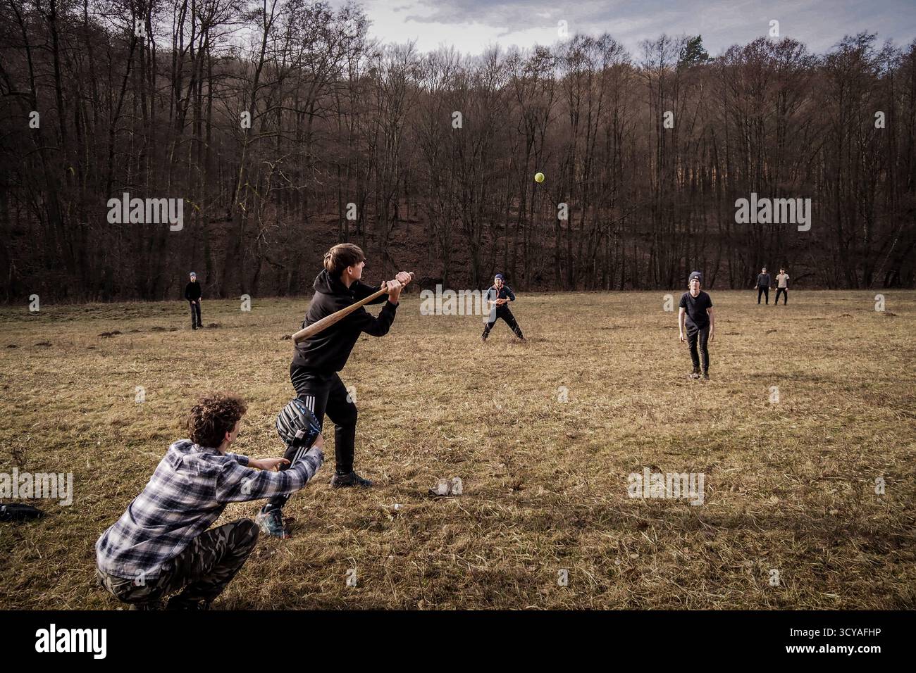 Gruppe von Pfadfindern, die während des Wintercamps in Ješkova Ves, Slowakei, ein Baseballspiel auf einer Wiese inmitten von Wäldern spielen. Stockfoto