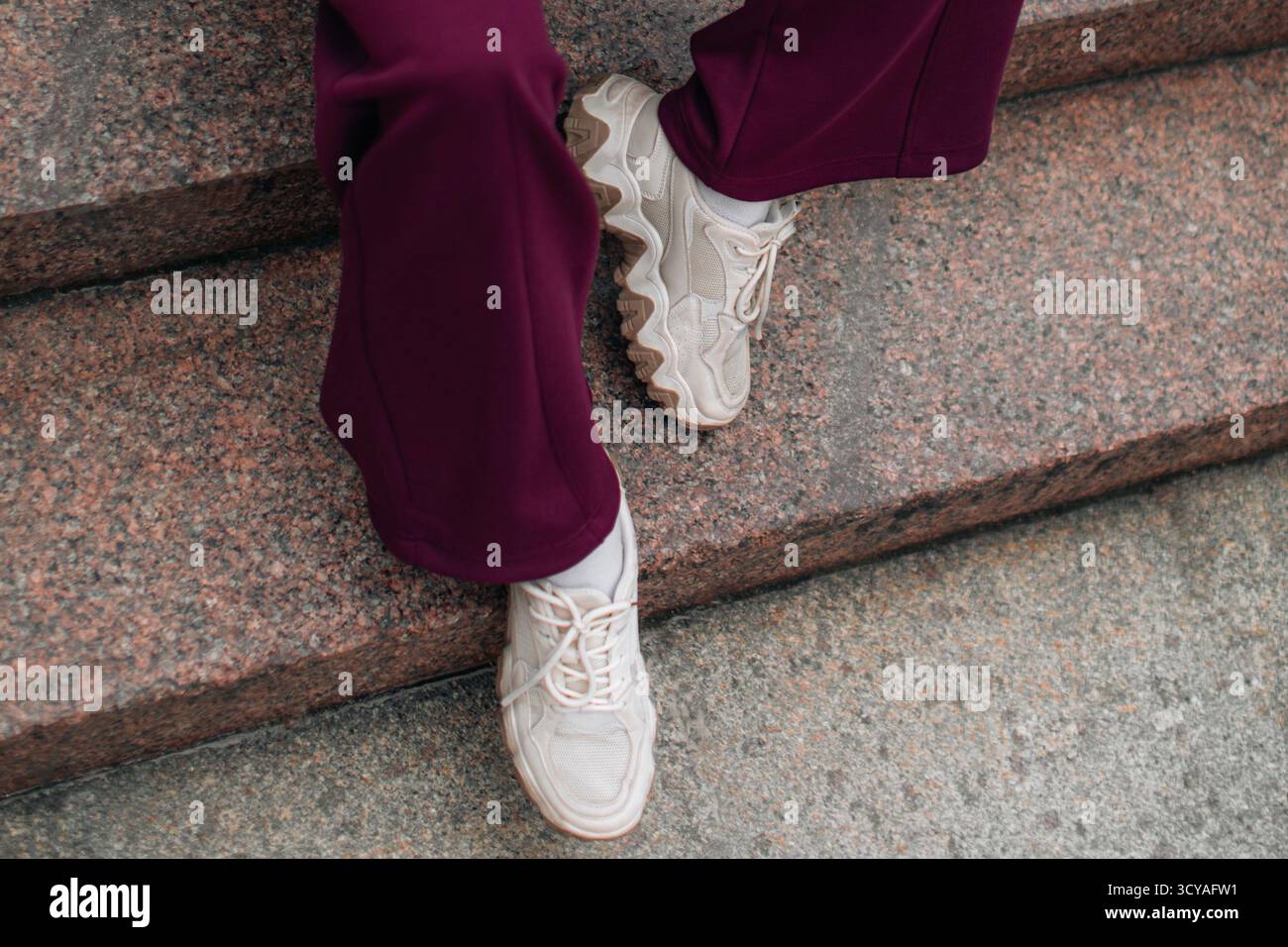 Sportliche Streetwear, beigefarbene Pufferweste und sportlicher brauner Anzug, stilvolles Herbst-Winter-Damenoutfit Stockfoto