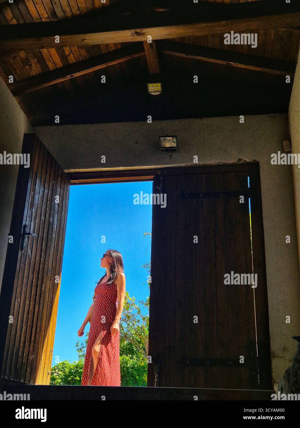 Tour durch das Weingut. Mädchen kommt aus dem alten Weinkeller. Mädchen, das in der Tür vor blauem Himmel steht. Stockfoto