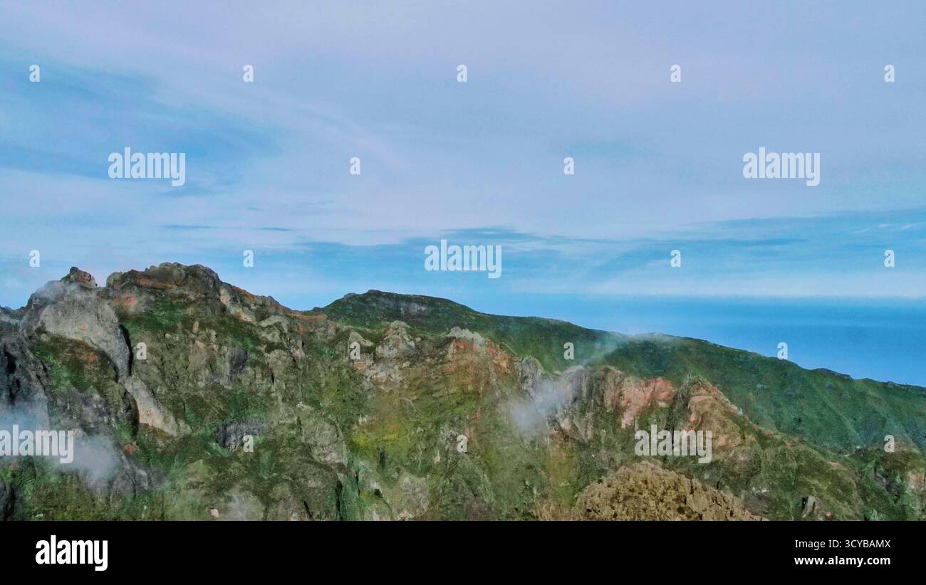 Neblige Berglandschaft mit dramatischen Klippen, Morgenlicht und rötlichen Felsen. Ätherische Wolken treiben durch grüne Täler. Perfekt für die Natur, Trav Stockfoto