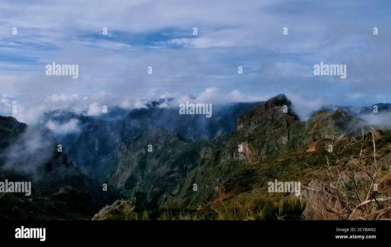 Neblige Berglandschaft mit dramatischen Klippen, Morgenlicht und rötlichen Felsen. Ätherische Wolken treiben durch grüne Täler. Perfekt für die Natur, Trav Stockfoto
