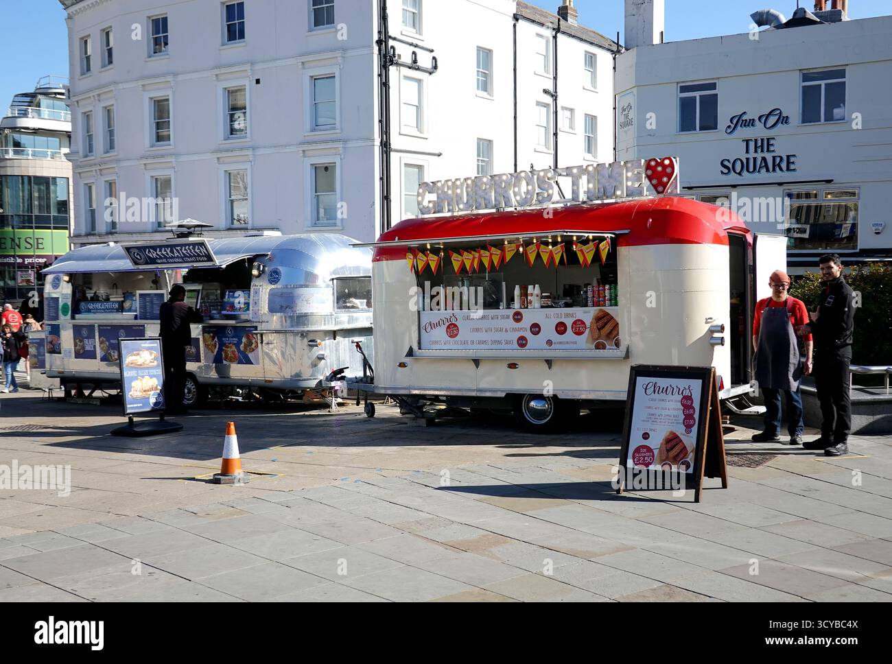 Street Food-Anbieter arbeiten mit umgebauten Airstream Caravans im Stadtzentrum von Brighton, England. Silberne Anhänger im Retro-Stil, in denen Speisen serviert werden Stockfoto