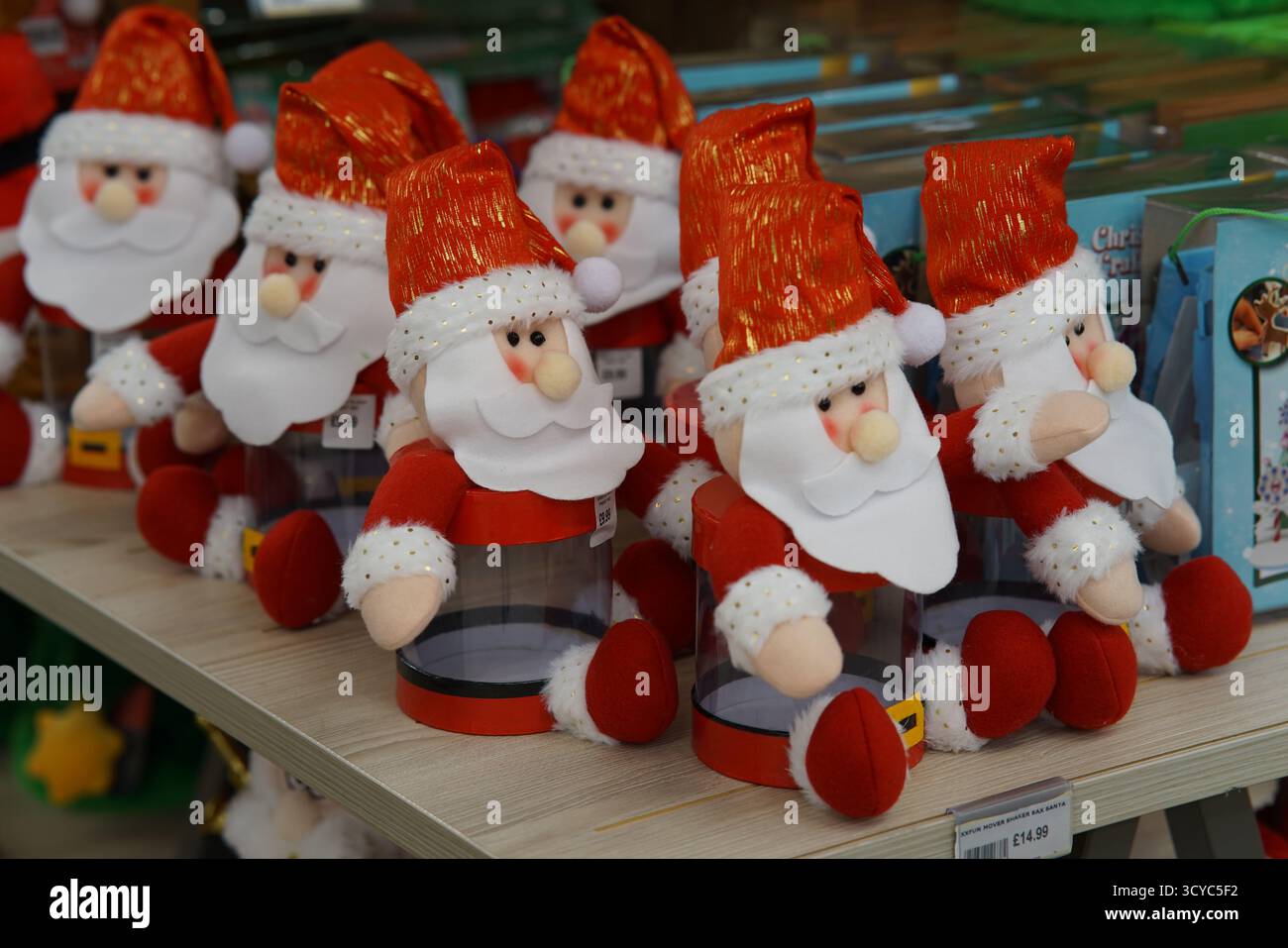 Eine Reihe von Plüschfiguren des Weihnachtsmanns mit funkelnden roten Hüten und weißen Bärten im Haskins Garden Centre. Stockfoto
