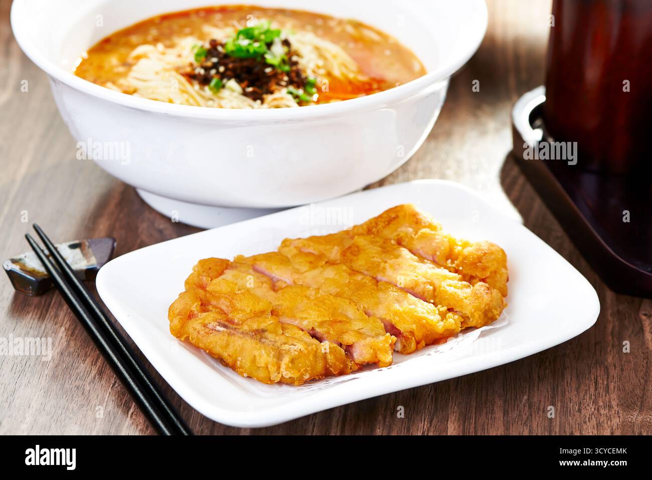 Knusprig gebratener Schweinekrebs mit scharfen Dan Dan Noodles mit Essstäbchen, serviert in Schüssel und Schüssel, Seitenansicht des authentischen chinesischen Essens Stockfoto
