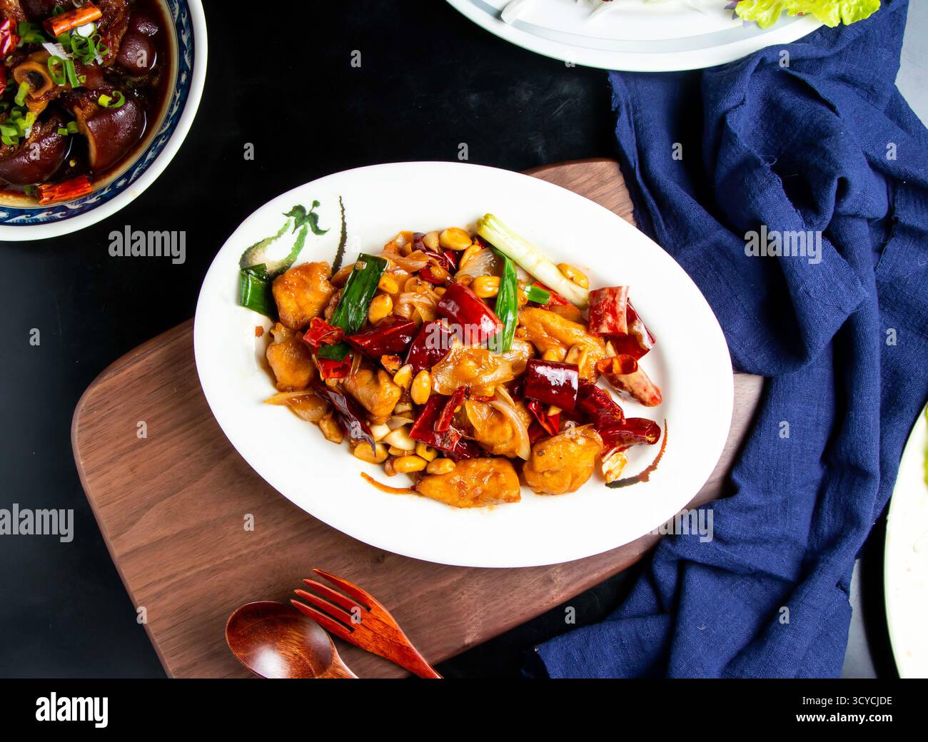 Kung Pao Huhn mit Löffel und Gabel serviert in einer Schüssel isoliert auf Holzbrett mit Blick auf taiwanisches Essen Stockfoto