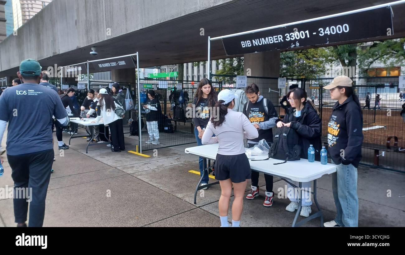 Toronto, ON, Kanada - 18. Oktober 2025: Läufer holen ihre Startnummern von Freiwilligen an einem Outdoor-Registrierungstisch vor der Veranstaltung ab. Stockfoto