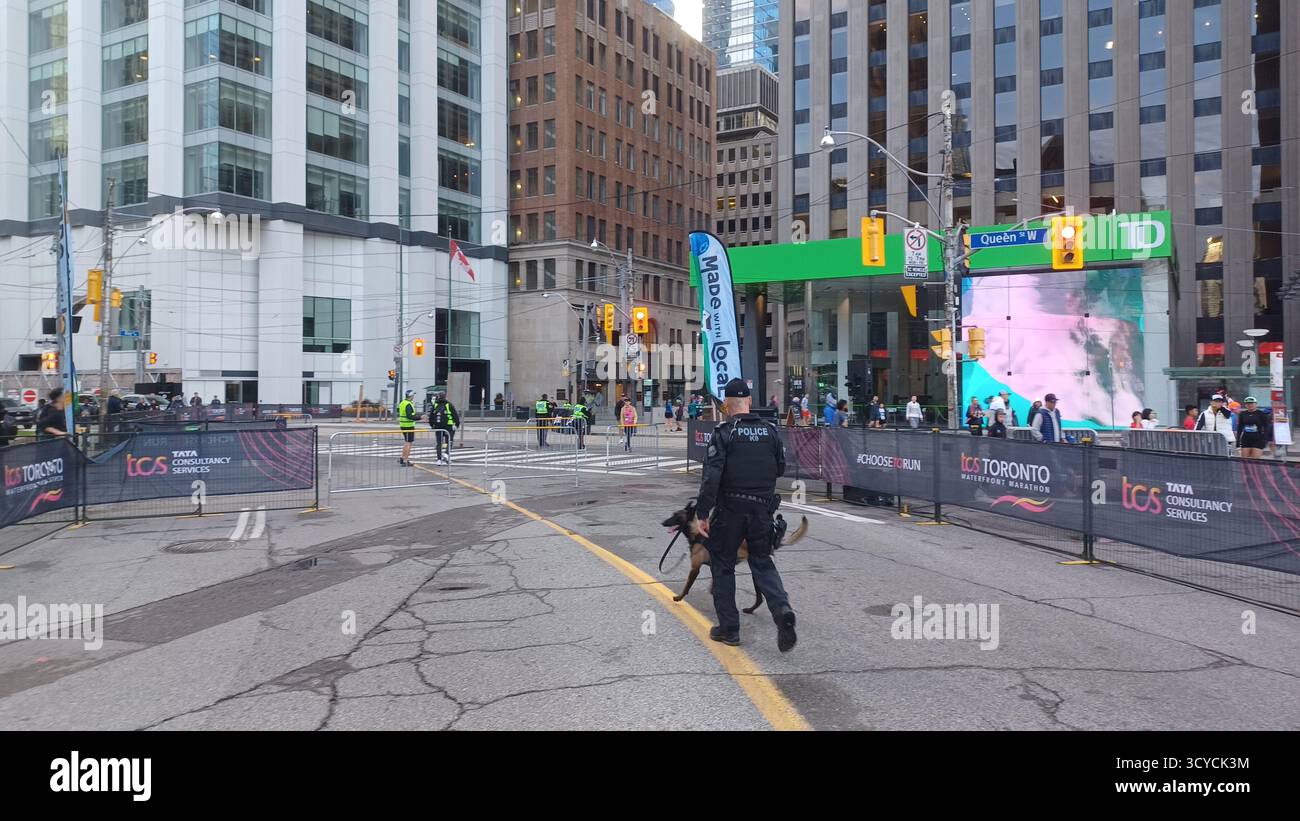 Toronto, ON, Kanada - 18. Oktober 2025: Ein Polizist und sein Hund der K9-Einheit patrouillieren auf der leeren, abgesperrten Straße vor dem Start eines Maras in der Stadt Stockfoto