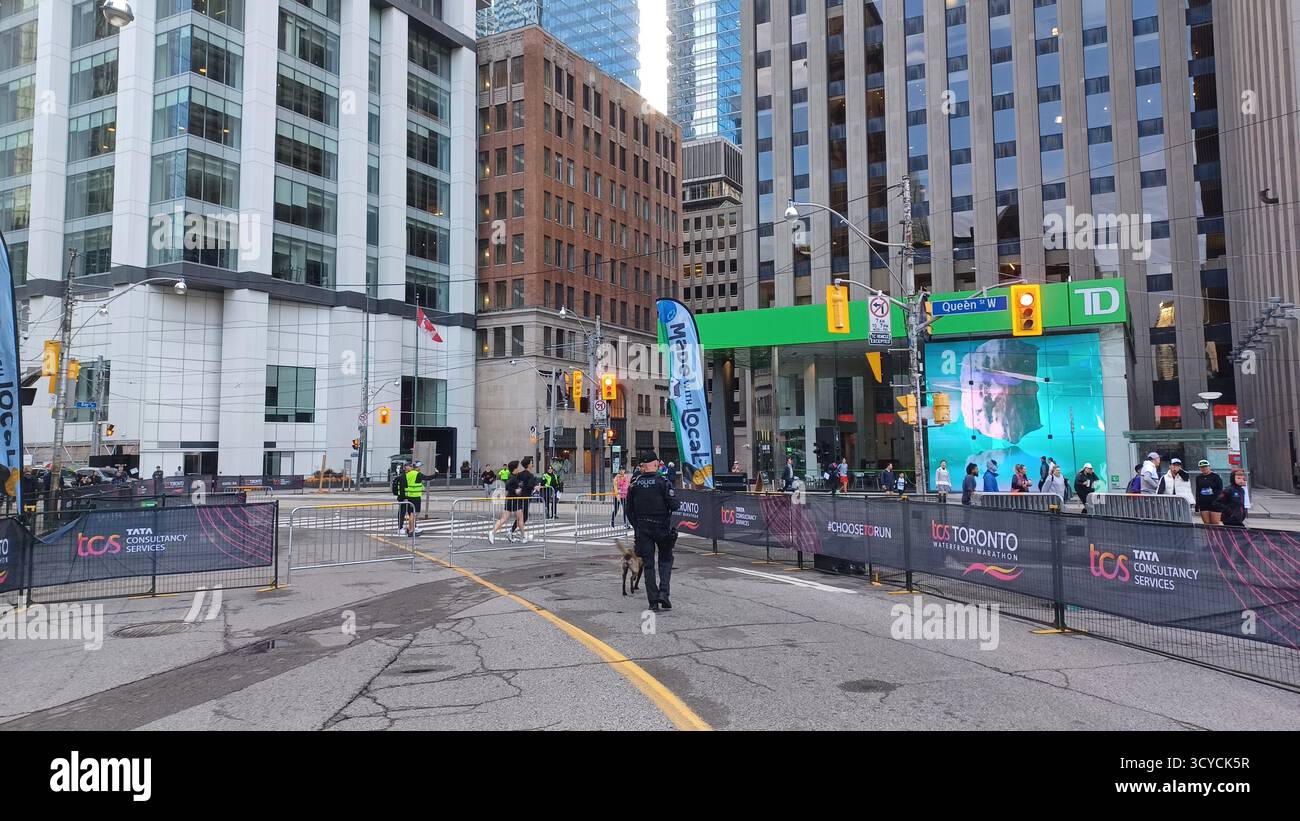Toronto, ON, Kanada - 18. Oktober 2025: Ein Polizist und sein Hund der K9-Einheit patrouillieren auf der leeren, abgesperrten Straße vor dem Start eines Maras in der Stadt Stockfoto