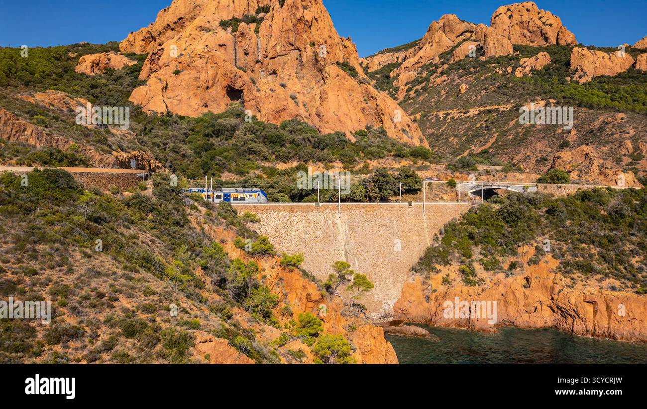 Panoramablick auf die Küste des Esterel-Gebirges mit gewundenen Straßen, Eisenbahnschienen und einem vorbeifahrenden Zug über dem Mittelmeer, französische Riviera Stockfoto