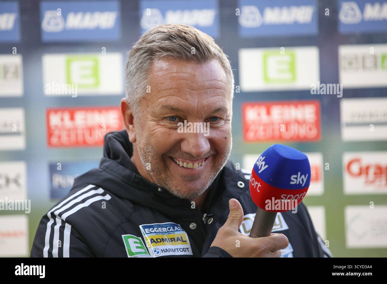 Österreichisches Bundesliga-Spiel zwischen Grazer AK 1902 und TSV Egger Glas Hartberg. Dynamische Fußball-Action, Spieler in Bewegung, Emotionen, Stadionatmosphäre und Teamgeist in professionellen Details. Das Bild zeigt Cheftrainer Manfred Schmid (Hartberg). Stockfoto
