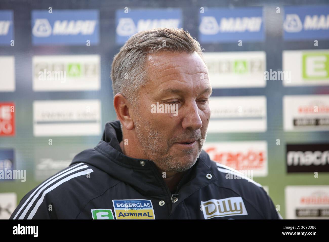 Österreichisches Bundesliga-Spiel zwischen Grazer AK 1902 und TSV Egger Glas Hartberg. Dynamische Fußball-Action, Spieler in Bewegung, Emotionen, Stadionatmosphäre und Teamgeist in professionellen Details. Das Bild zeigt Cheftrainer Manfred Schmid (Hartberg). Stockfoto