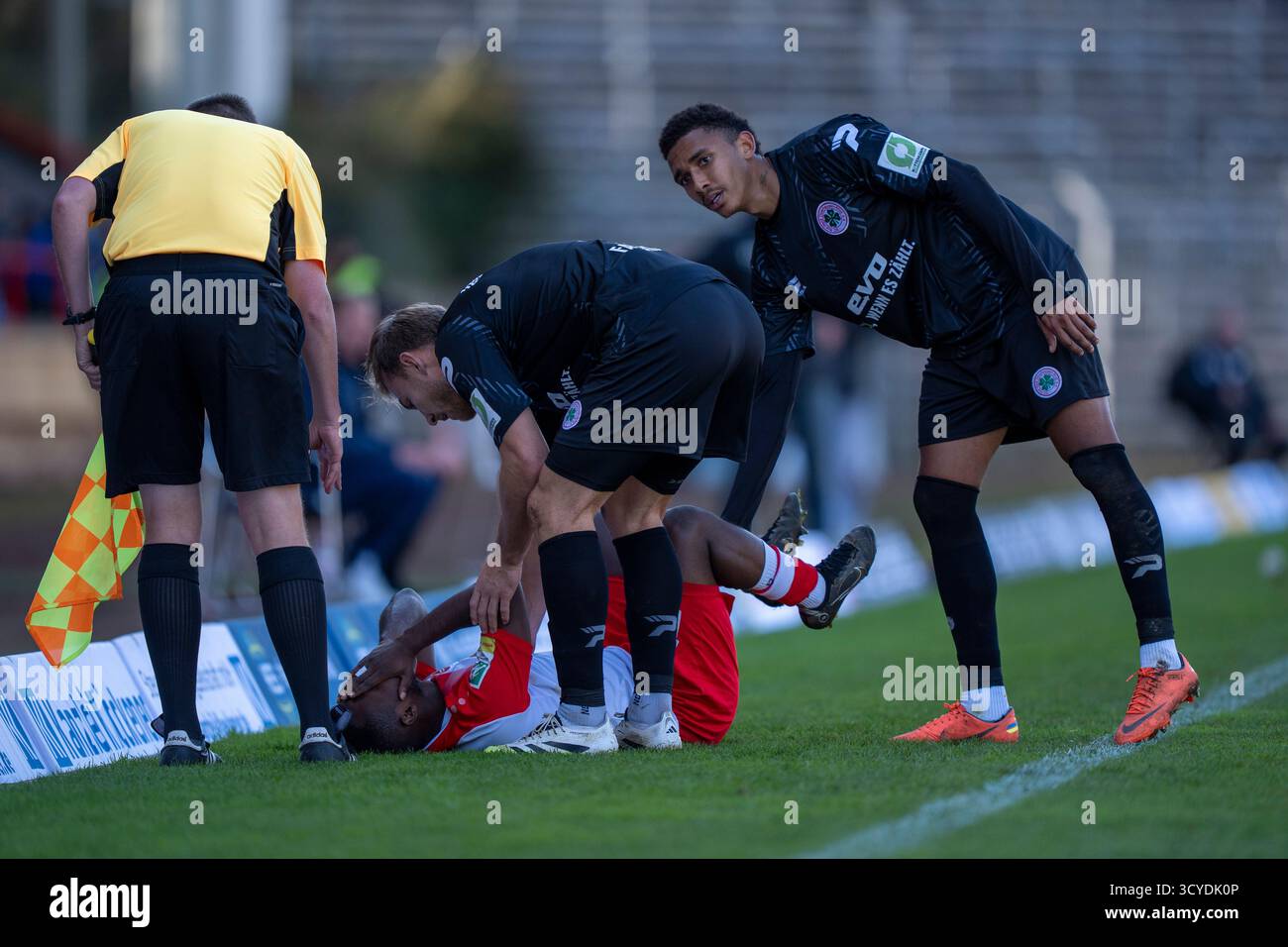 Siegen, Deutschland. Oktober 2025. Derrick Kyere (Sportfreunde Siegen, #11) liegt vor Schmerzen am Boden. Pierre Fassnacht (Rot Weiss Oberhausen, #3) und Eric Gueye (Rot Weiss Oberhausen, #11) kümmern sich um ihn Sportfreunde Siegen - Rot-weiß Oberhausen 18.10.2025 Fussball, Regionalliga West, 12. Spieltag, Deutschland, Siegen, Leimbachstadion Credit: dpa/Alamy Live News Stockfoto