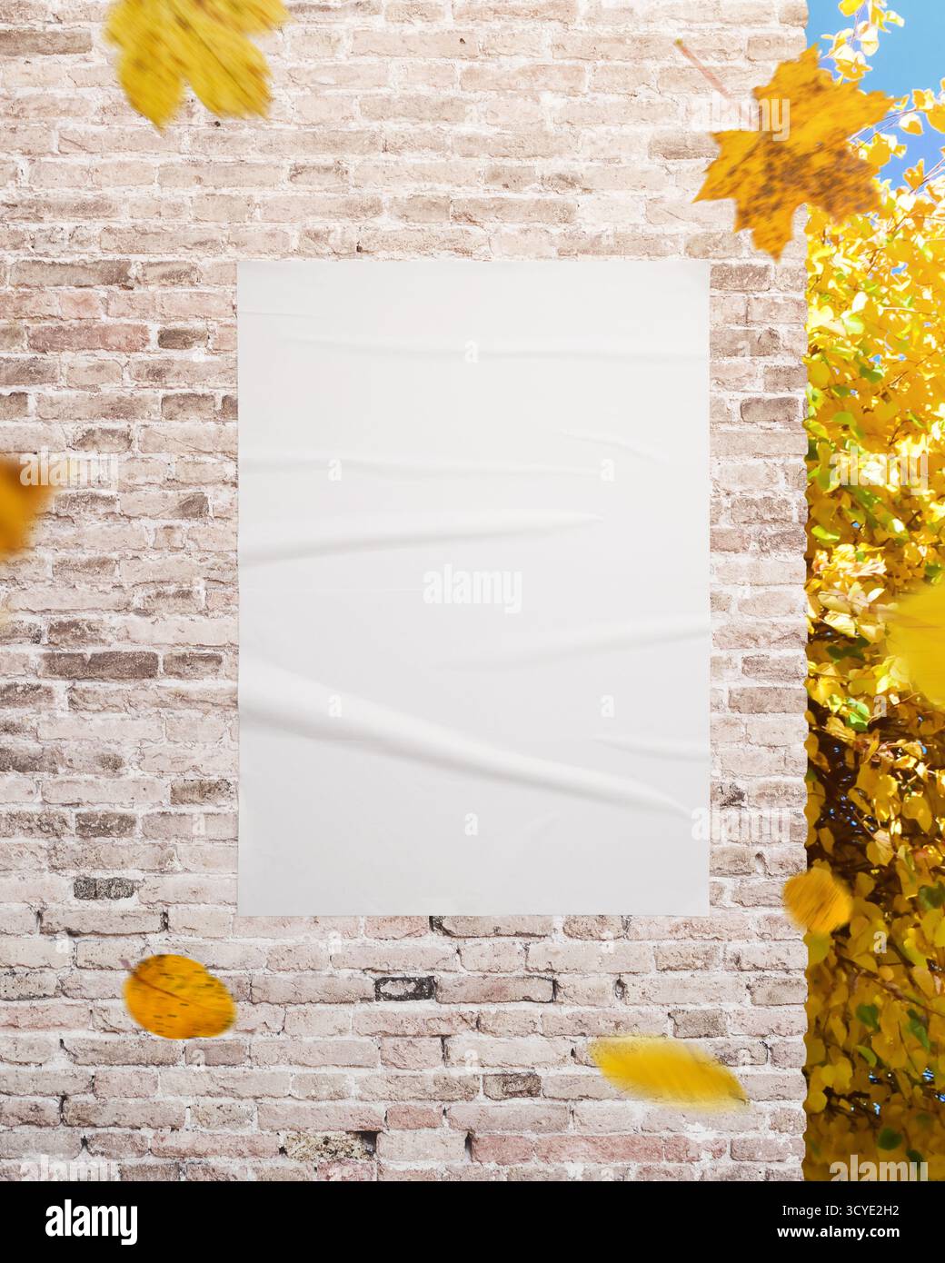 Vertikales weißes Poster an strukturierter Wand mit gelben Blättern, perfekt für Werbung, Kampagnengrafiken und Designpräsentationen Stockfoto