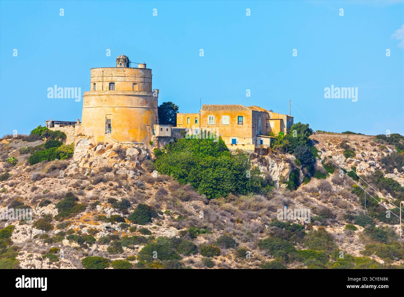 Torre di Calamosca und der Leuchtturm Capo Sant Elia stehen auf einem felsigen Hügel in Cagliari, Sardinien. Die historischen Bauten sind von Trockenheit umgeben Stockfoto