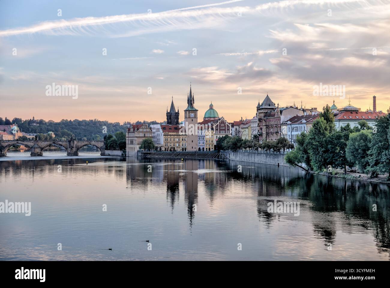 Vormittagsblick über die Moldau in Richtung historischer Türme und Gebäude der Prager Altstadt, Tschechien, mit Reflexionen im ruhigen Wasser. Stockfoto