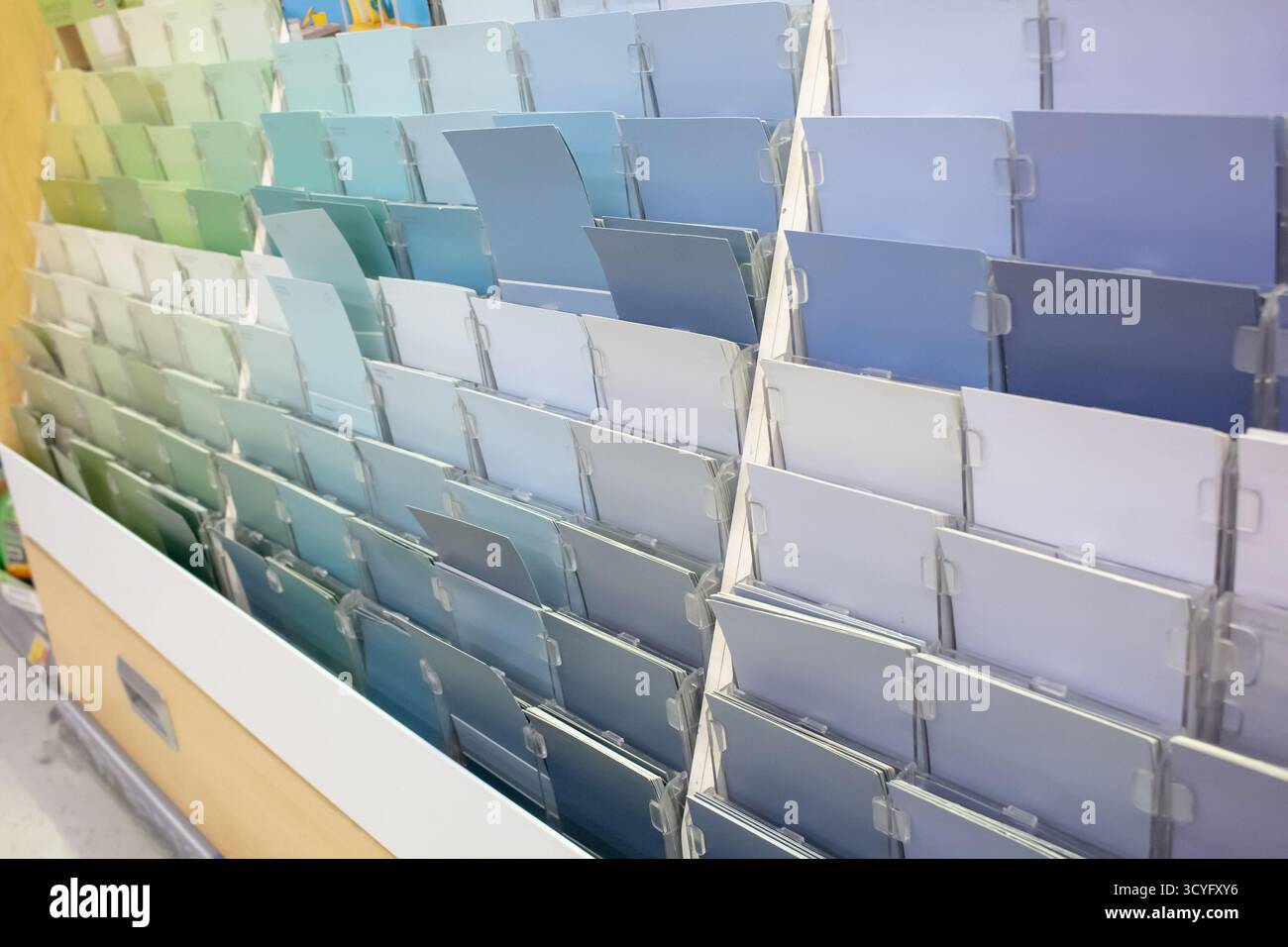 Eine Ansicht einer Vielzahl von Papiermustern in kühlen Farbtönen, die auf einem Regal in der Lackierabteilung eines lokalen Heimwerkergeschäfts zu sehen sind. Stockfoto