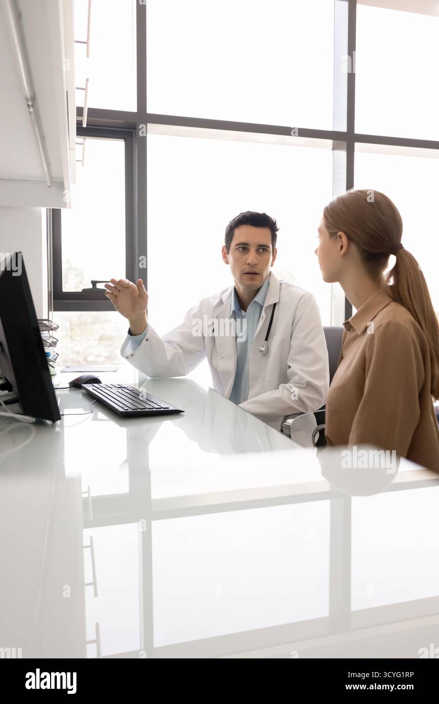 Junger Hausarzt-Leitgespräch mit weiblicher Patientin in der Klinik Stockfoto