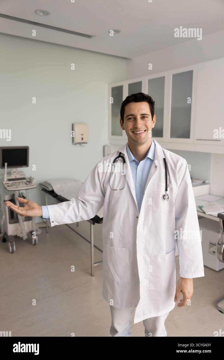Fröhlicher männlicher Arzt lächelt und Gesten mit der Hand, empfängt den Patienten Stockfoto