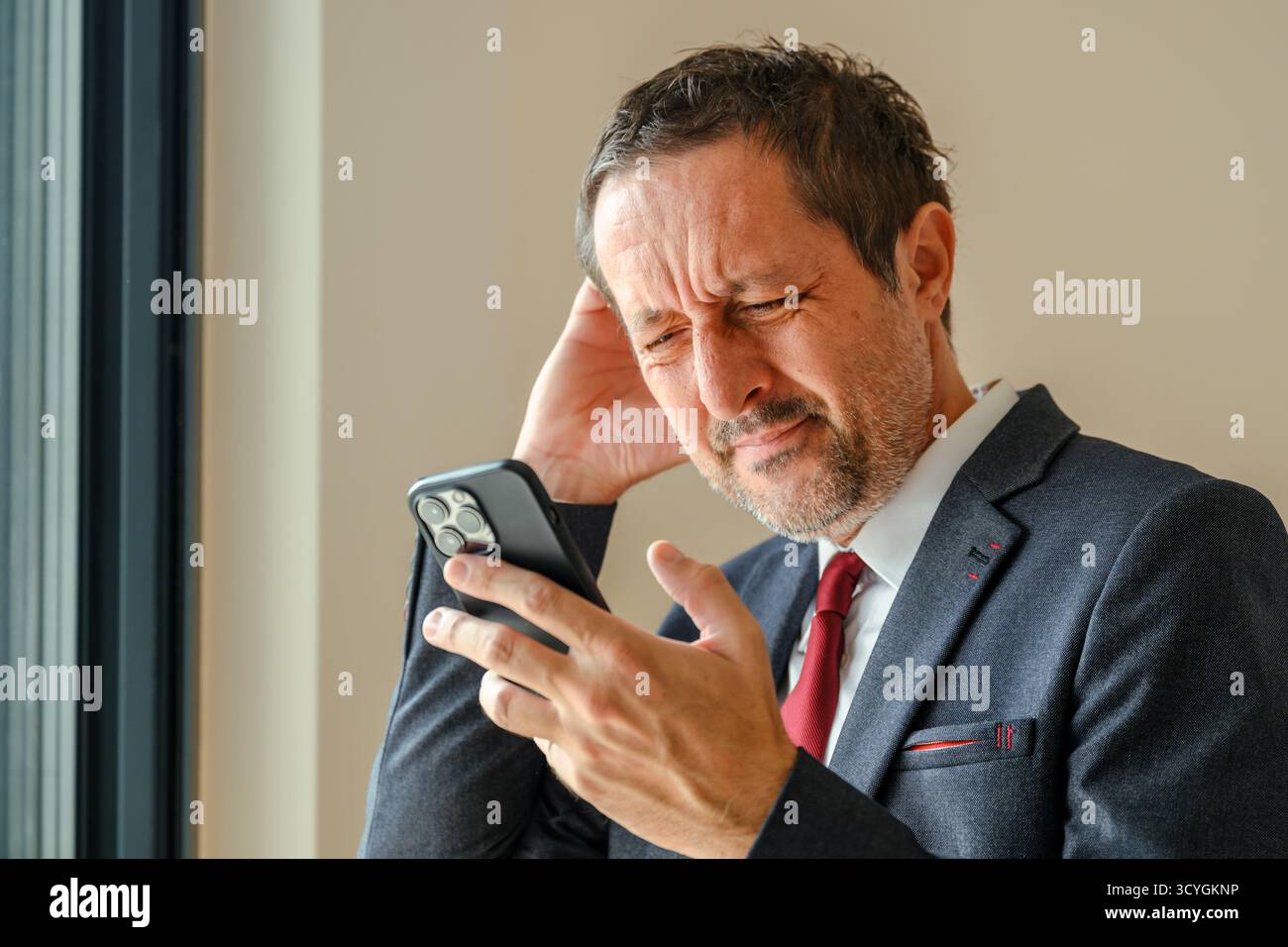 Gestresster Geschäftsmann, der unangenehme Textnachrichten auf dem Smartphone liest, vergesslicher Unternehmer im Büro, besorgt, nachdem er schlechte Nachrichten bei wo erhalten hatte Stockfoto