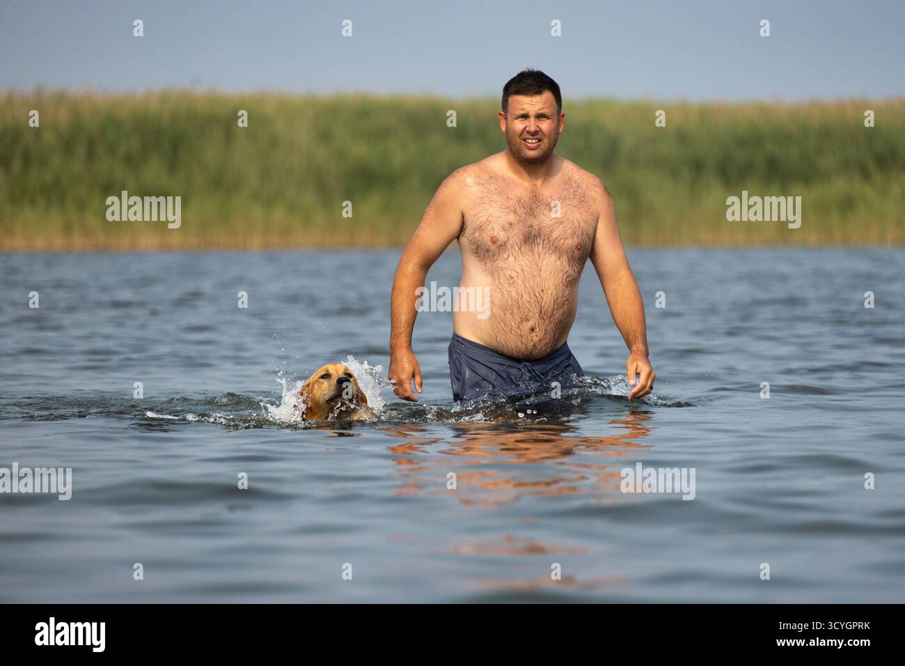 Ein Mann, der mit einem Hund im Wasser läuft Stockfoto