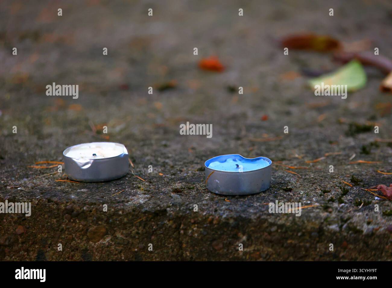 Zwei gebrauchte Lichtkerzen auf einer Betonoberfläche draußen auf dem Friedhof Stockfoto