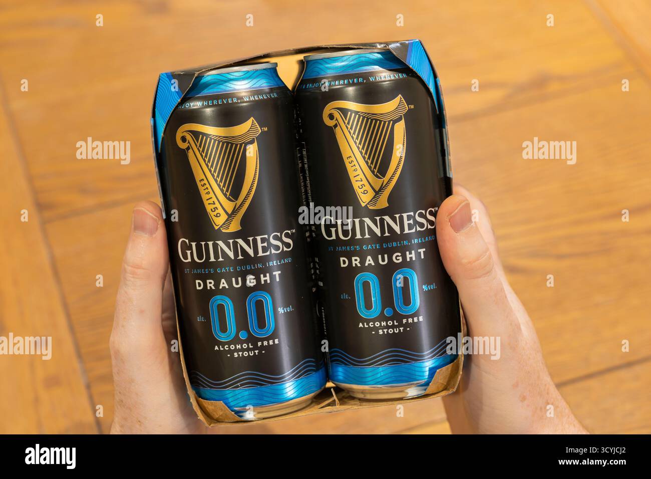 Ein Mann mittleren Alters, der ein Viererpack Guinness Zero 0,0 alkoholfreies Stout Bier hält, das mit einer kalten Filtrationsmethode hergestellt wurde, um den Alkohol zu entfernen. England Stockfoto