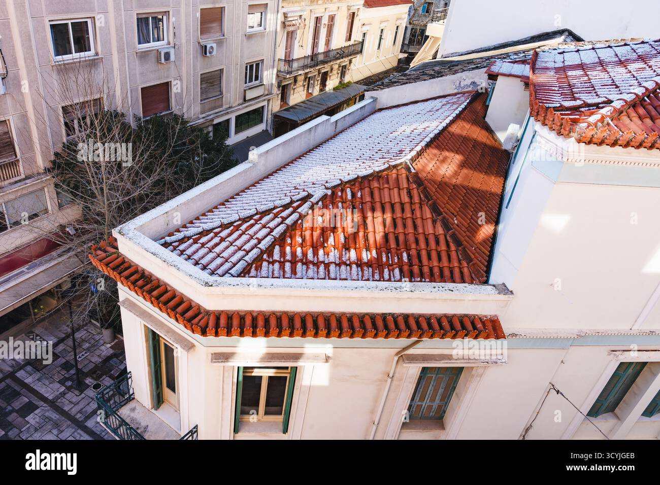 Dünne Schneedecke liegt auf roten Terrakottadächern in Athen, erster Schnee, Stadtbild Stockfoto