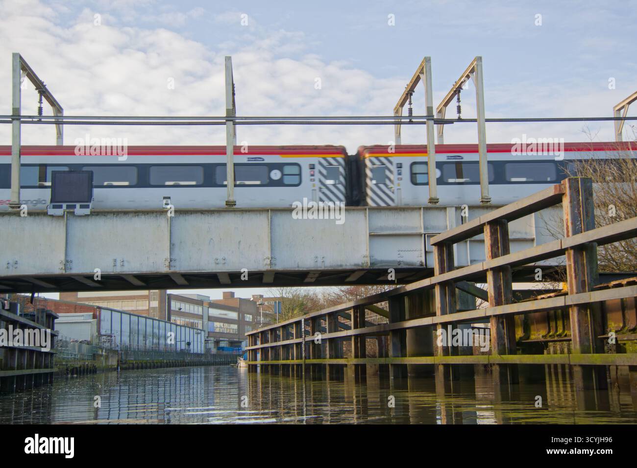 Greater Anglia Zug auf der Trowse Swing Bridge über den Fluss Wensum in Norwich, Norfolk, Großbritannien. Stockfoto