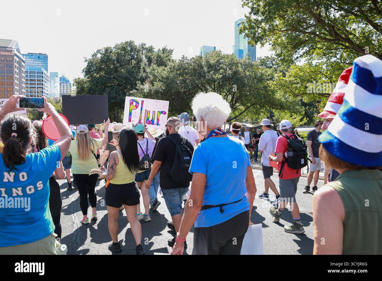 Die Menschen marschieren friedlich in der Innenstadt von Austin, Texas, mit bunten Schildern, die Gleichheit und Einheit während des No Kings Day Protest fördern. Stockfoto