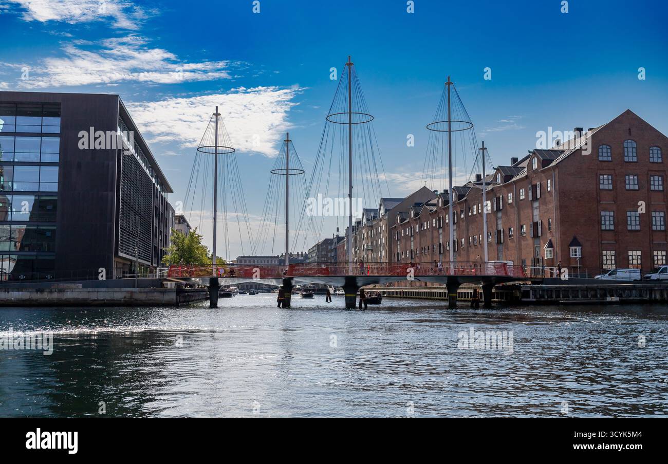 Kopenhagen, Dänemark-14. August 2025: Cirkelbroen, eine moderne Fußgängerbrücke mit segelartigen Pylonen, verbindet Hafenviertel mit historischen Lagerhäusern Stockfoto