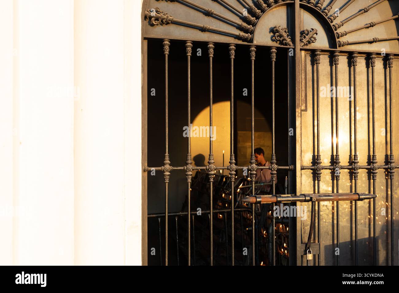 El Rocio, Sevilla, Andalusien, Spanien. August 2025. Eine ältere Frau zündet Kerzen in einer Kapelle als Teil einer religiösen Praxis an. Stockfoto