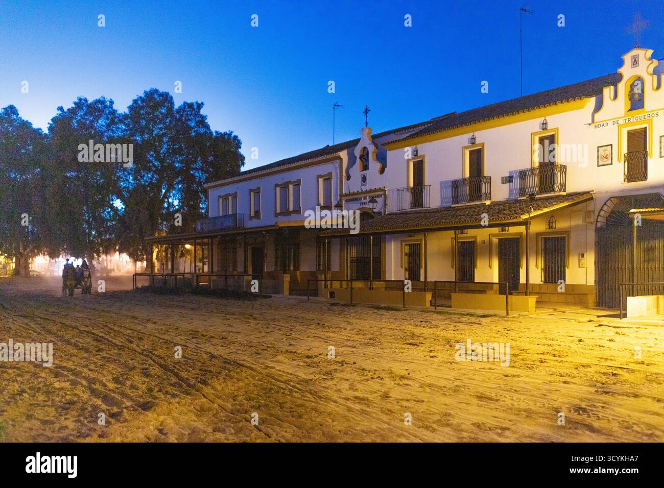 El Rocio, Sevilla, Andalusien, Spanien. August 2025. Hermandad Haus mit rot-weißer Fassade, beleuchtet von Straßenlaterne in der Abenddämmerung im Dorf El Rocio. Stockfoto